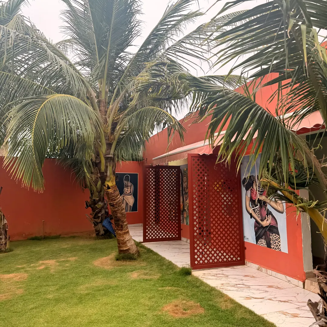 Cour intérieure ornée de fresques, de cocotiers et de claustras rouges
