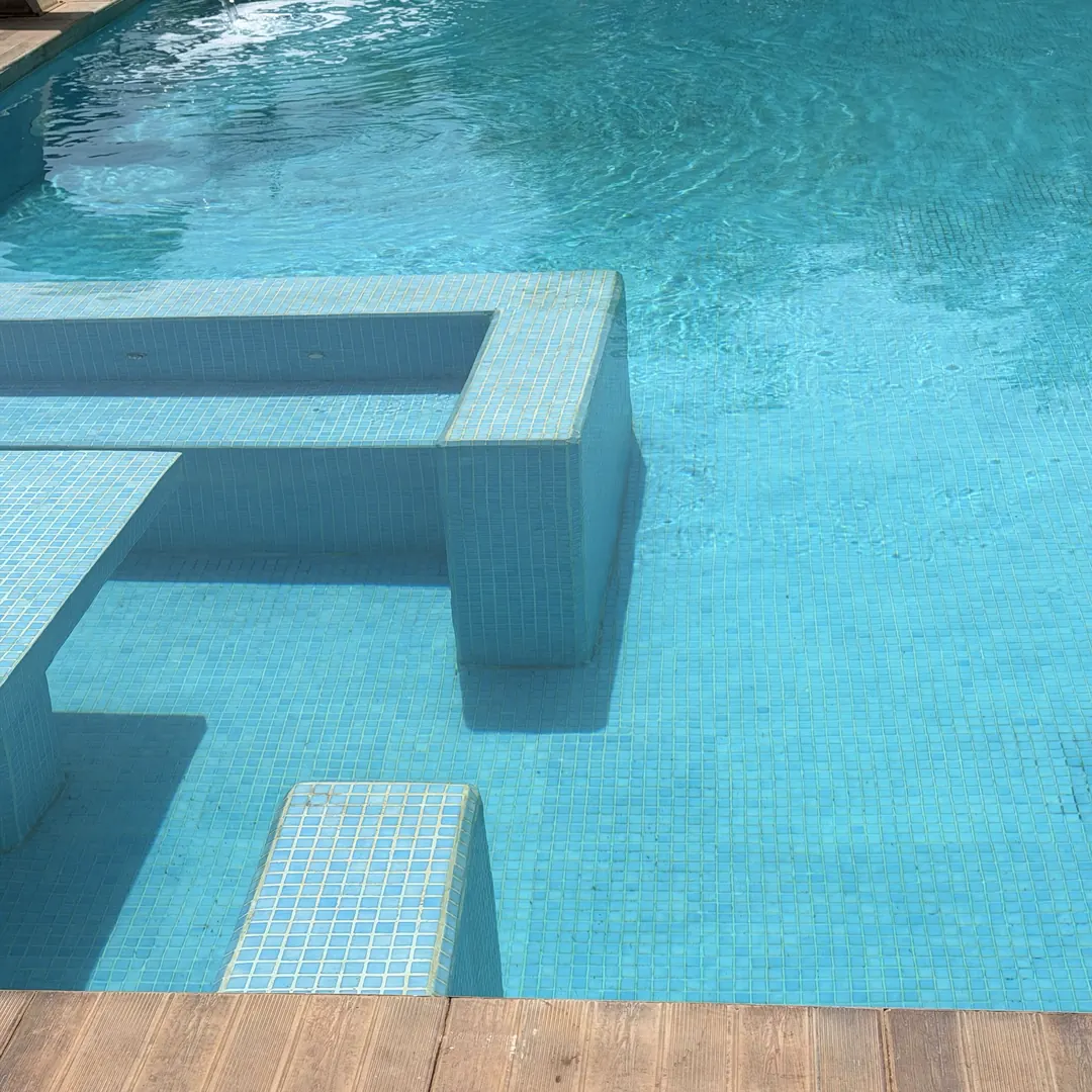 Eau turquoise et banquettes immergées de la piscine